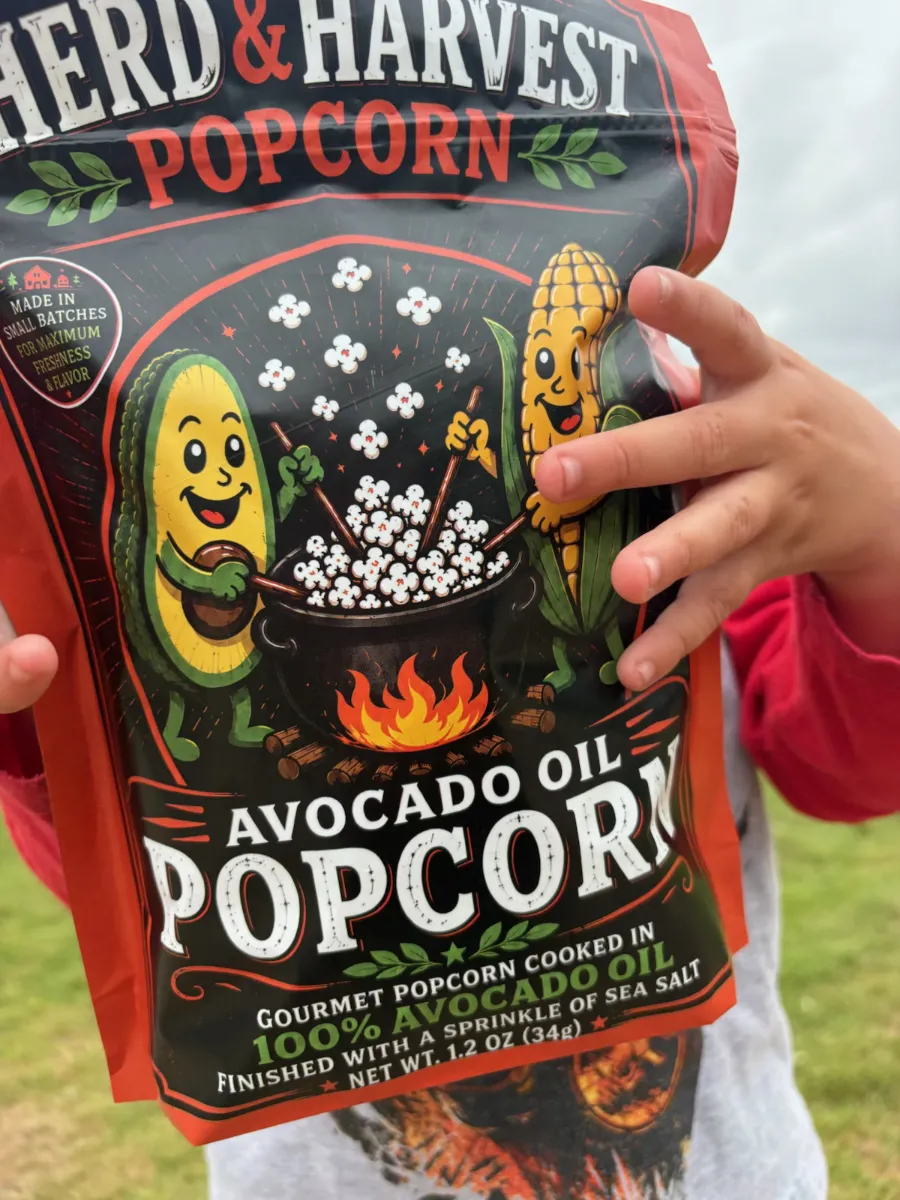 Child holding Herd & Harvest Avocado Oil Popcorn bag — small-batch, no seed oils